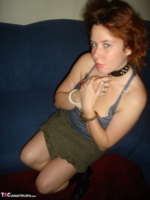 Collared redhead with blue eyes wearing gag ball and handcuffs before posing naked on the blue couch - Picture 2