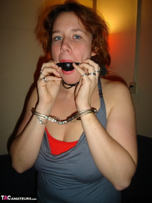 Collared redhead with blue eyes wearing gag ball and handcuffs before posing naked on the blue couch - Picture 4