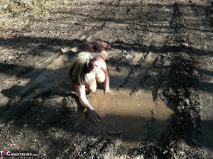 Mature gal in rubber boots sheds her coat before covering her naked body with mud and peeing in the puddle - Picture 12
