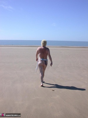 Mature blonde in white top and jeans miniskirt peeing outdoors before exposing her huge breast on the beach - Picture 13