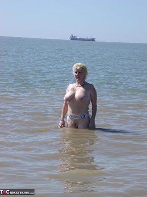 Mature blonde in white top and jeans miniskirt peeing outdoors before exposing her huge breast on the beach - Picture 15