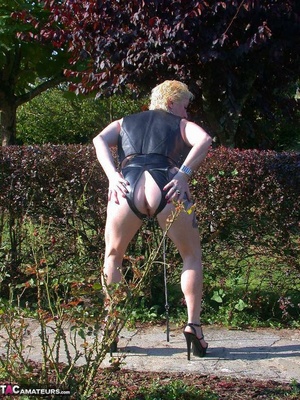 Busty blonde on a leash posing in leather outfit outdoors and slowly undressing to expose her pierced snatch - Picture 4