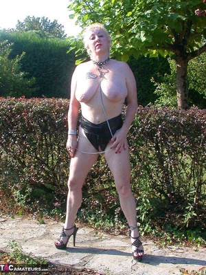 Busty blonde on a leash posing in leather outfit outdoors and slowly undressing to expose her pierced snatch - Picture 12