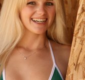 Blonde teen in high heels slowly taking off green bikini outdoors before