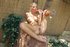 Sitting nude on a low concrete wall she stuffs a pink dildo in her mouth