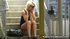 Sporting a tight, little, black dress, she smokes and sits on the stairs
