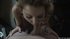 Curly blonde hair flowing, she drives her face forward, opening her throat
